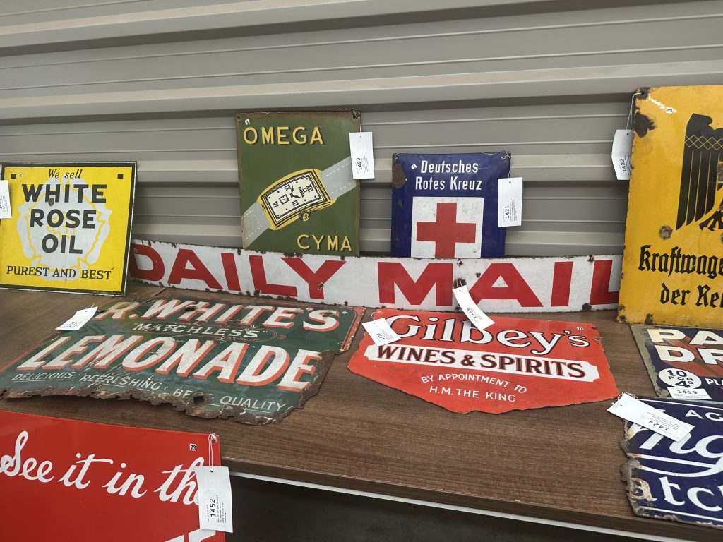Vintage enamel advertising signs including Daily Mail, White Rose Oil and Gilbey’s displayed at auction